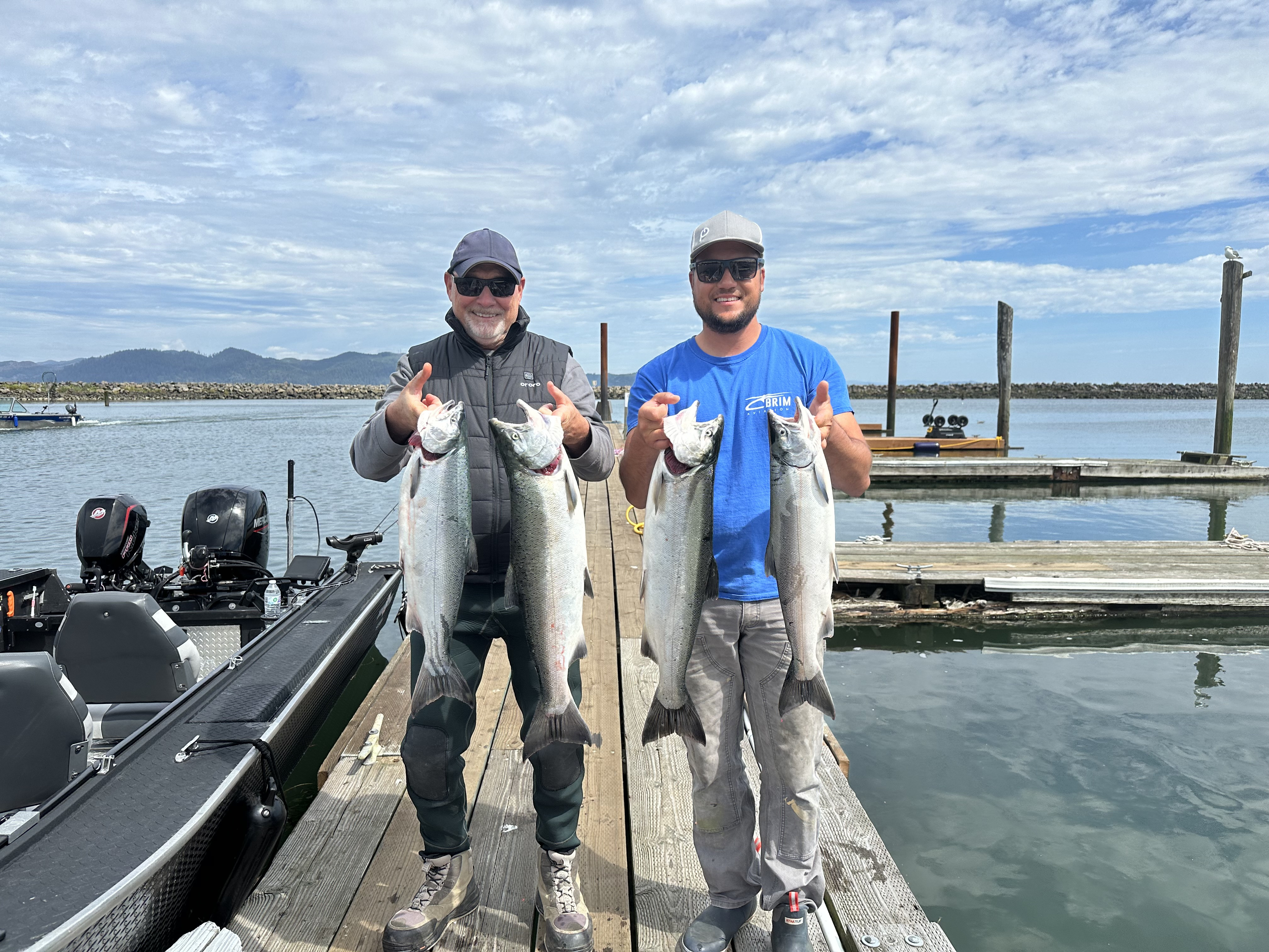 Two anglers holding salmon near the dock in Warrenton Oregon