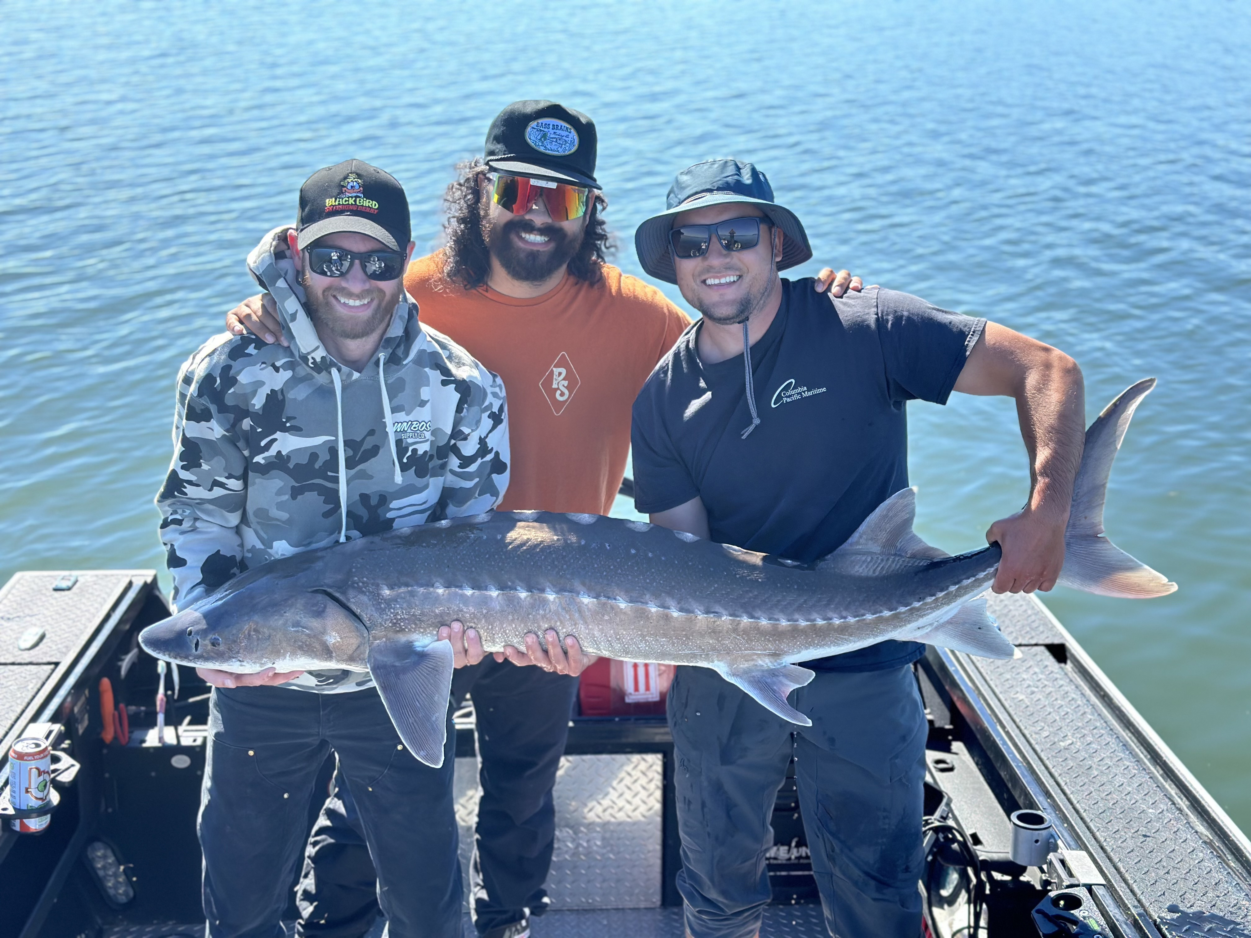 Three anglers holding a large sturgeon on a guided fishing trip